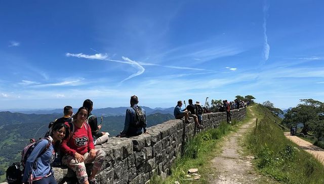 Hikers sitting on ancient stone wall enjoying panoramic mountain views on ridge trail