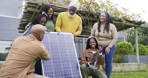 Multigenerational family installing solar panels in backyard promoting sustainable energy