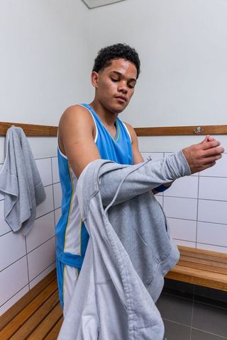 Teen athlete wearing hoodie over basketball outfit