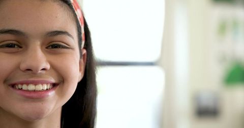Child smiling in natural light wearing red-and-white headband