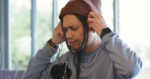 Podcaster adjusting headphones while preparing to record in cozy daylight studio
