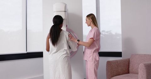 Woman Receiving Mammogram While Technologist Guiding Detector Positioning