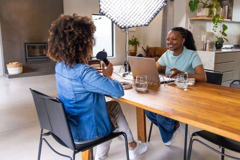 African american hosts recording podcast at home with laptop, microphone, softbox lighting