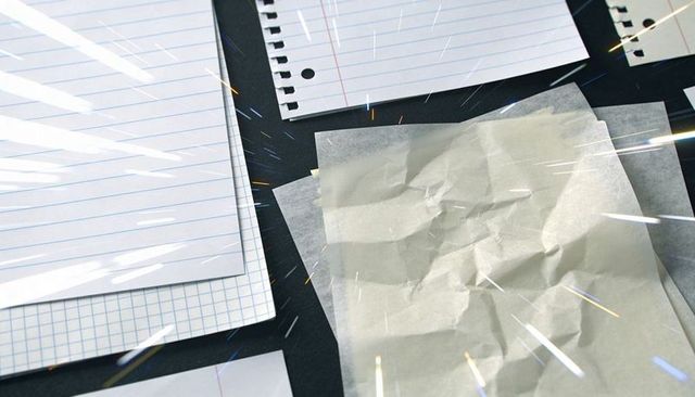 Crumpled Tracing Paper with Lined Notebook and Graph Sheet on Dark Desk with Light Streaks