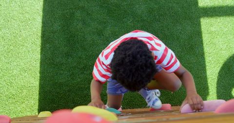 Child Climbing Playground Rock Wall on Sunny Day