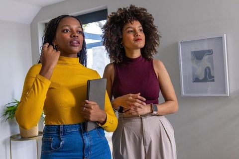 African american women standing holding tablet in modern living room with minimalist decor