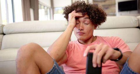 Stressed young man relaxing on couch holding remote