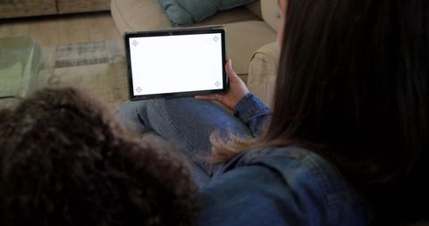 Parent and child watching tablet together on sofa for family bonding
