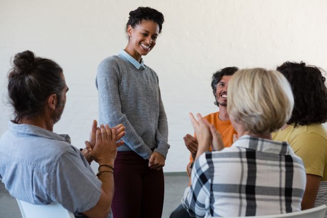 Group of friends in casual attire applauding a woman standing in an art class. Ideal for use in educational materials, community engagement content, teamwork and collaboration themes, and promotional materials for workshops or creative classes.