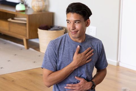 African american man practicing mindful breathing with hands on chest and abdomen at home