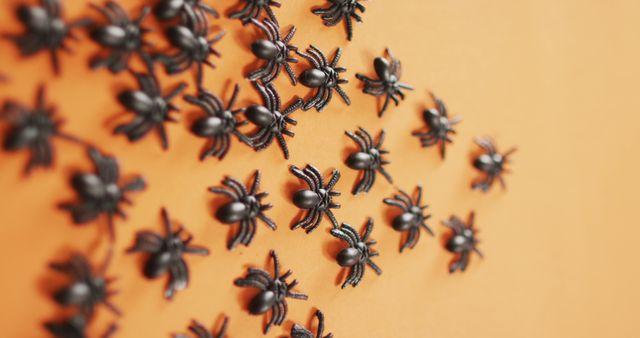 Close up of multiple spider toys with copy space against orange background. halloween festivity and celebration concept