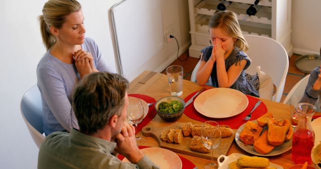 High angle view of Caucasian family praying together at dining table in a comfortable home - Download Free Stock Photos Pikwizard.com
