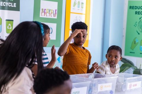 African american kids sorting recycling in classroom learning sustainability and teamwork