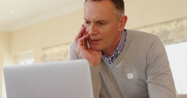 Caucasian businessman reviews content on a laptop at home - Download Free Stock Photos Pikwizard.com