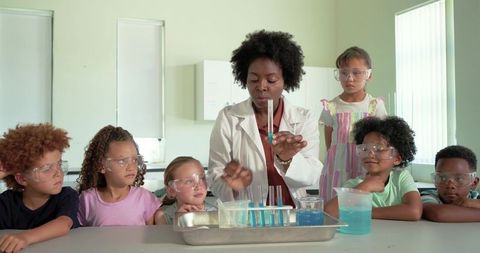 Stem teacher demonstrating colorful chemistry experiment with elementary students