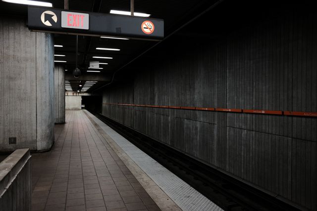 Empty subway platform with modern design and clear exit signs, featuring concrete walls and minimalistic lighting. Suitable for themes of urban life, public transportation, modern architecture, and travel. Ideal for blog posts, articles, websites, and advertisements focused on metro systems, commuting, and city infrastructure.