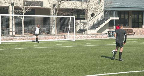 Soccer players practicing goal shots on school field