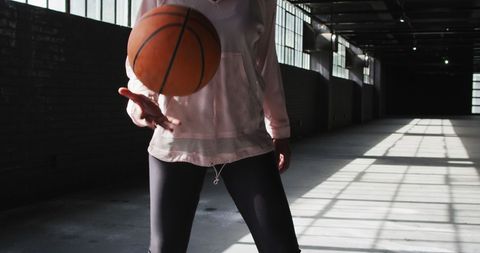 Young Woman Practicing Basketball in Abandoned Warehouse