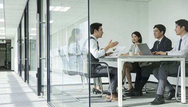 Business team presenting data in glass conference room, executives collaborating on strategy