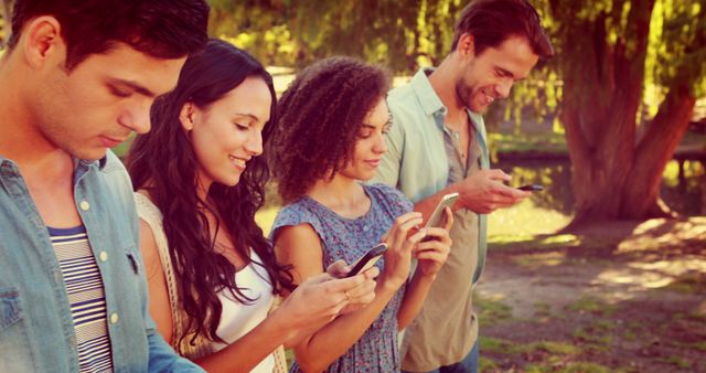 Group of young friends standing in a park while browsing their smartphones. Great for illustrating social media trends, technology usage, and youth lifestyle. Can be used in advertisements for tech products, social media apps, or articles related to modern communication and connectivity.
