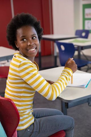 Smiling African American Teen in Classroom with Notebook
