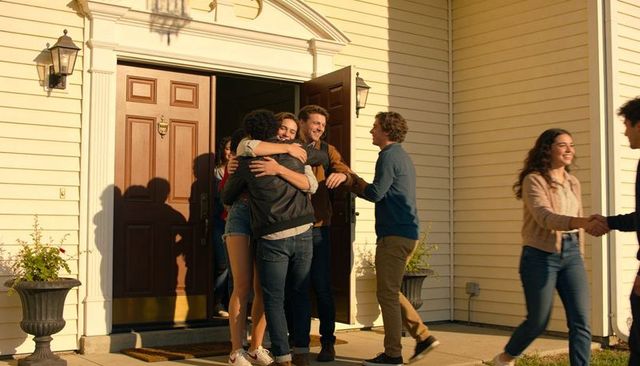 Friends hugging on suburban front porch at golden hour — casual reunion and greeting