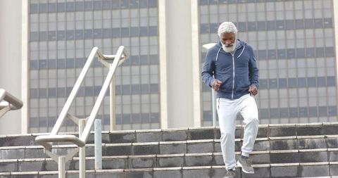 Senior african american man walking down urban stairs in hoodie showing active aging