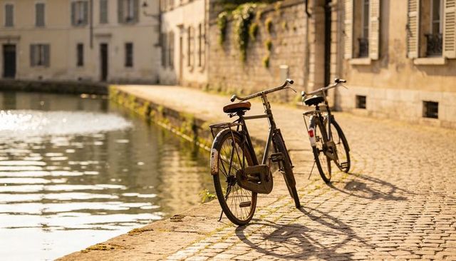 Vintage bicycles leaning on cobblestone canal path at golden hour with water reflections
