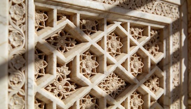 Intricate marble jali carving with floral rosettes and geometric lattice shadows