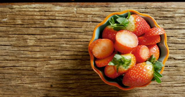 This photo shows fresh, red strawberries in a decorative bowl placed on a rustic wooden table. Perfect for use in advertisements promoting healthy eating, organic fruits, and farm-fresh produce. Great for food blogs, restaurant menus, and social media posts about health and nutrition.