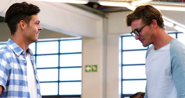 Two Young Men Engaging in Conversation at Modern Office - Download Free Stock Images Pikwizard.com