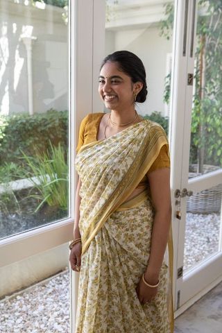 Indian woman in elegant yellow saree by sunlit glass doors