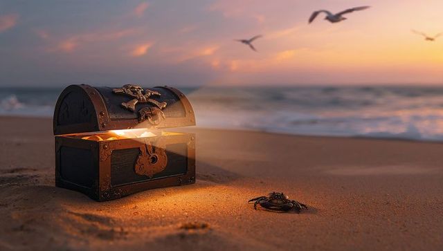 Glowing treasure chest on sunset shoreline emitting golden light with crab and seagulls