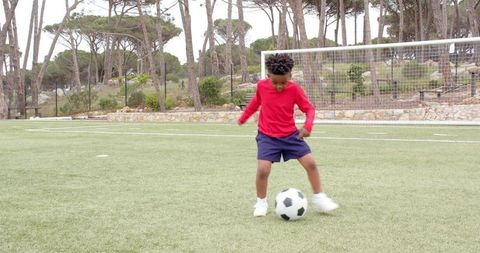 Young Boy Dribbling Soccer Ball on Park Turf Field