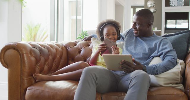Image of african american father and daughter using tablet. Enjoying quality family time together at home, using technology.