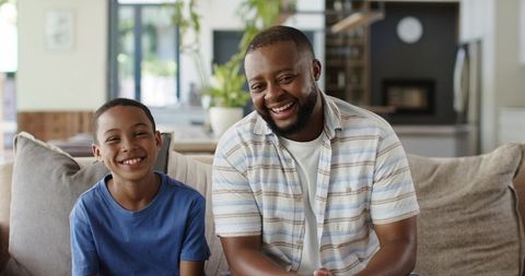 African american father and son smiling on sofa sharing warm family bond at home