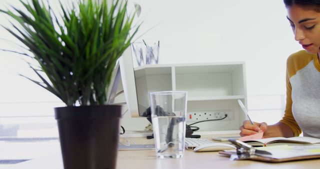 Professional Woman Writing Notes at Desk in Office Setting - Download Free Stock Images Pikwizard.com