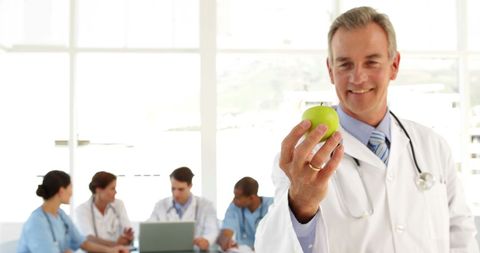 Senior Doctor Presenting Healthy Lifestyle Concept with Apple
