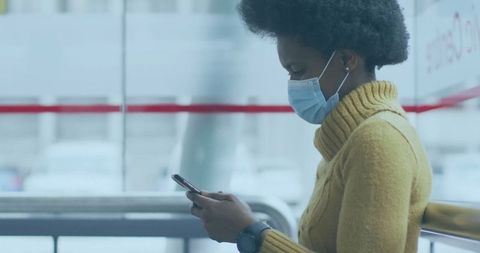Woman Wearing Mask Using Smartphone in Transit Terminal