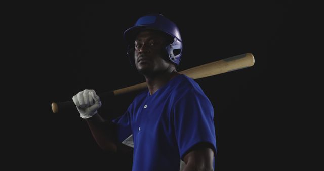 Focused Baseball Player in Blue Jersey Holding Bat Against Dark Background - Download Free Stock Images Pikwizard.com