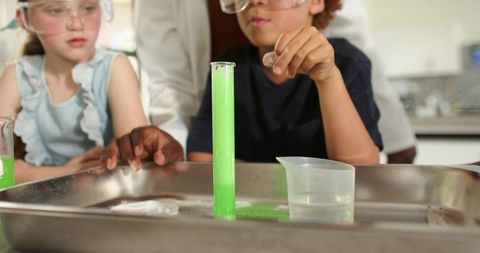 Elementary students conducting neon foam chemistry experiment wearing safety goggles