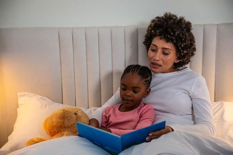 Mother Reading Bedtime Story to Daughter in Cozy Bedroom Setting