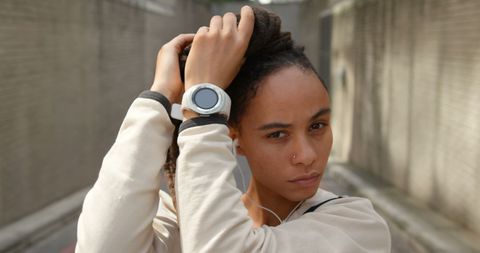 Young Woman with Smartwatch Adjusting Hair in Urban Environment