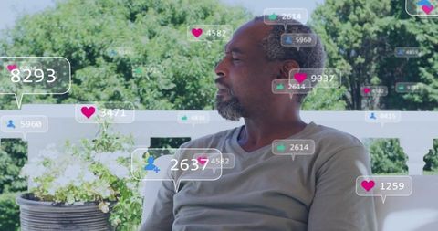 Mature man contemplating on veranda with floating social media likes and follower counts
