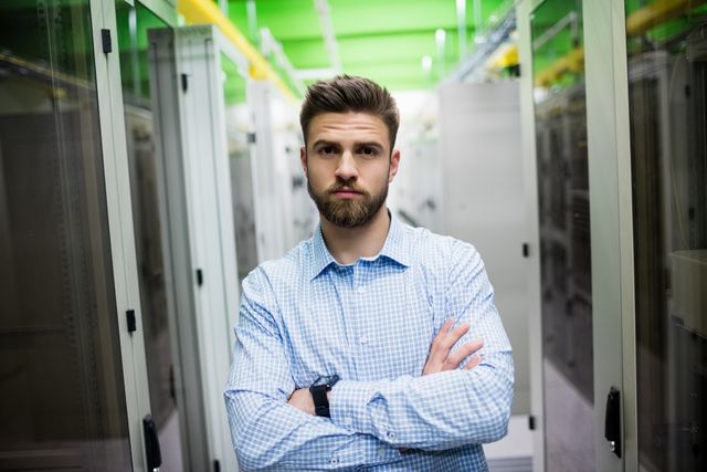 Technician standing with arms crossed in a server room - Download Free Stock Photos Pikwizard.com