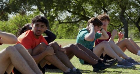 Multiethnic men training together outdoors performing sit-ups for teamwork and fitness