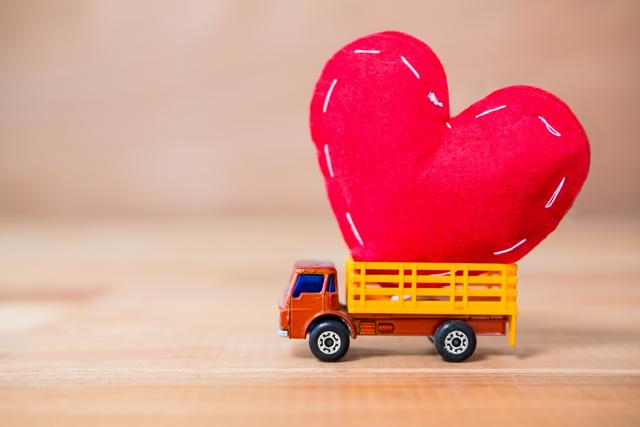This image shows a miniature truck carrying a large red heart, symbolizing the delivery of love and affection. Ideal for use in Valentine's Day promotions, romantic greeting cards, love-themed advertisements, and social media posts celebrating relationships and affection.