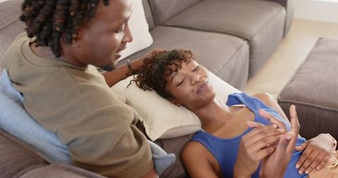 African american couple reclining on sectional sofa sharing intimate relaxed moment