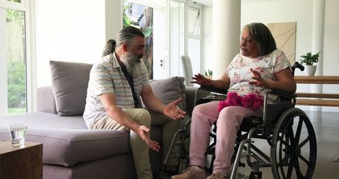 Senior couple at home sharing supportive moment in wheelchair