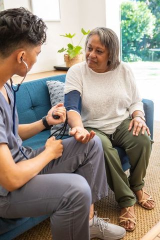 Professional Caregiver Checking Senior's Blood Pressure in Home Setting